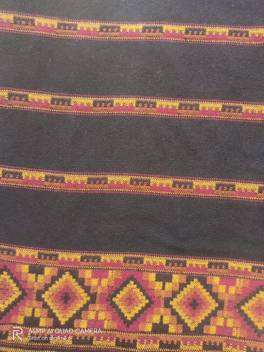 A close-up of the Hand Woven PASHMINA BLACK Shawl by aruna kullu handloom, featuring colorful geometric embroidery in yellow, red, and orange on dark wool fabric—showcasing traditional ethnic patterns for women.