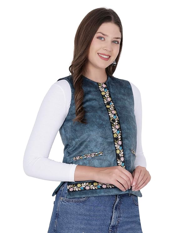 sadri for women A woman with long brown hair is smiling and wearing the aruna kullu handloom Nehru jacket for women in blue with embroidery work over a white long-sleeve shirt and blue jeans, posing against a white background.