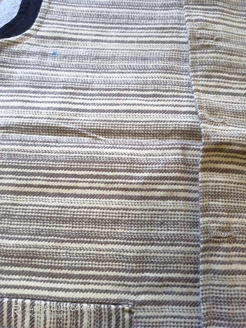 Close-up of an aruna kullu handloom Nehru Jacket in PURE ANGORA WOOL (BLACK & GREY), showcasing its coarse handwoven texture with horizontal black and grey stripes, a pocket at the lower left, and a curved neckline at the top left.