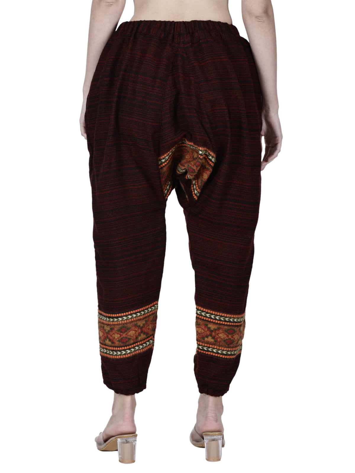 A barefoot person is shown from the back wearing aruna kullu handloom's loose yoga pajama maroon singal patti, featuring an elastic waistband and patterned detailing near the ankles and inner thighs.