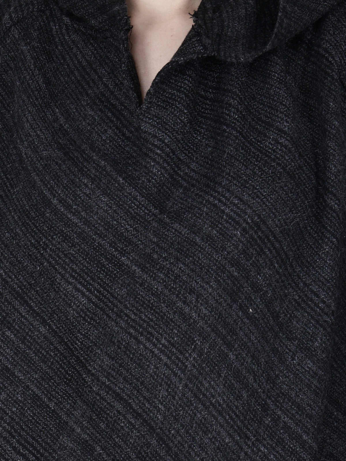 Close-up of a person wearing the aruna kullu handloom kullu shawl woolen poncho with hood singal patti black, featuring thick, textured fabric and visible handwoven embroidery with a slightly open collar revealing the neck.