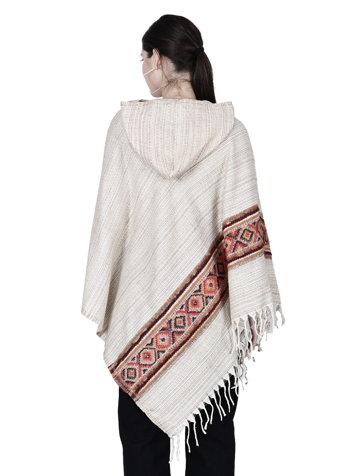 A woman is shown from the back wearing the Aruna Kullu Handloom cream kullu shawl woolen poncho with hood for ladies, featuring red and brown geometric patterns and fringed edges, against a white background.