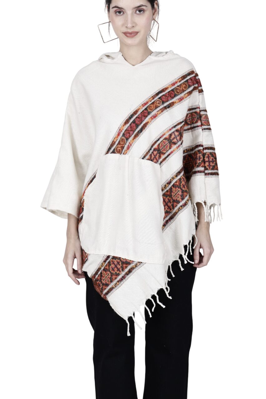 A woman stands facing forward in an aruna kullu handloom "kullu shawl woolen poncho with hood for ladies white 3 patti," featuring red and black geometric patterns and fringed edges, perfect as a party wear poncho.
