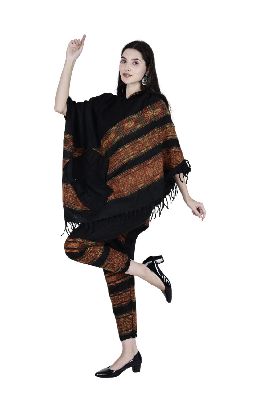 A woman with long dark hair models the aruna kullu handloom kullu shawl combo poncho and pajama black 3 patti, posing on one leg in black shoes against a white background.
