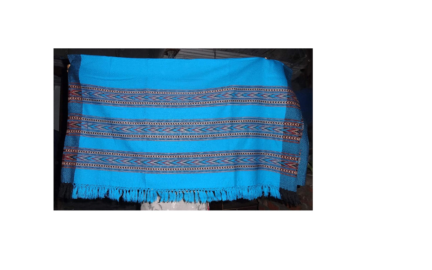 The aruna kullu handloom ANGORA Shawl in frozen color showcases beautiful Kullu weaving with colorful geometric patterns and fringed edges, designed for women and girls. The bright fabric is displayed against a dark background.