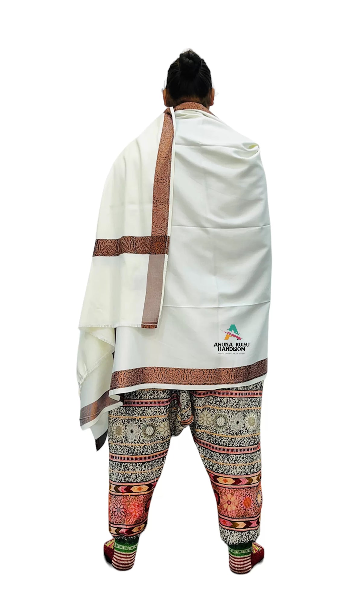 A person stands facing away, wearing aruna kullu handloom's Genuine Hand Woven pashmina Wool LOI (Men Shawl) in white, with patterned borders and intricate pants. The woolen shawl features the Arunachal Pradesh Tourism logo on the back.