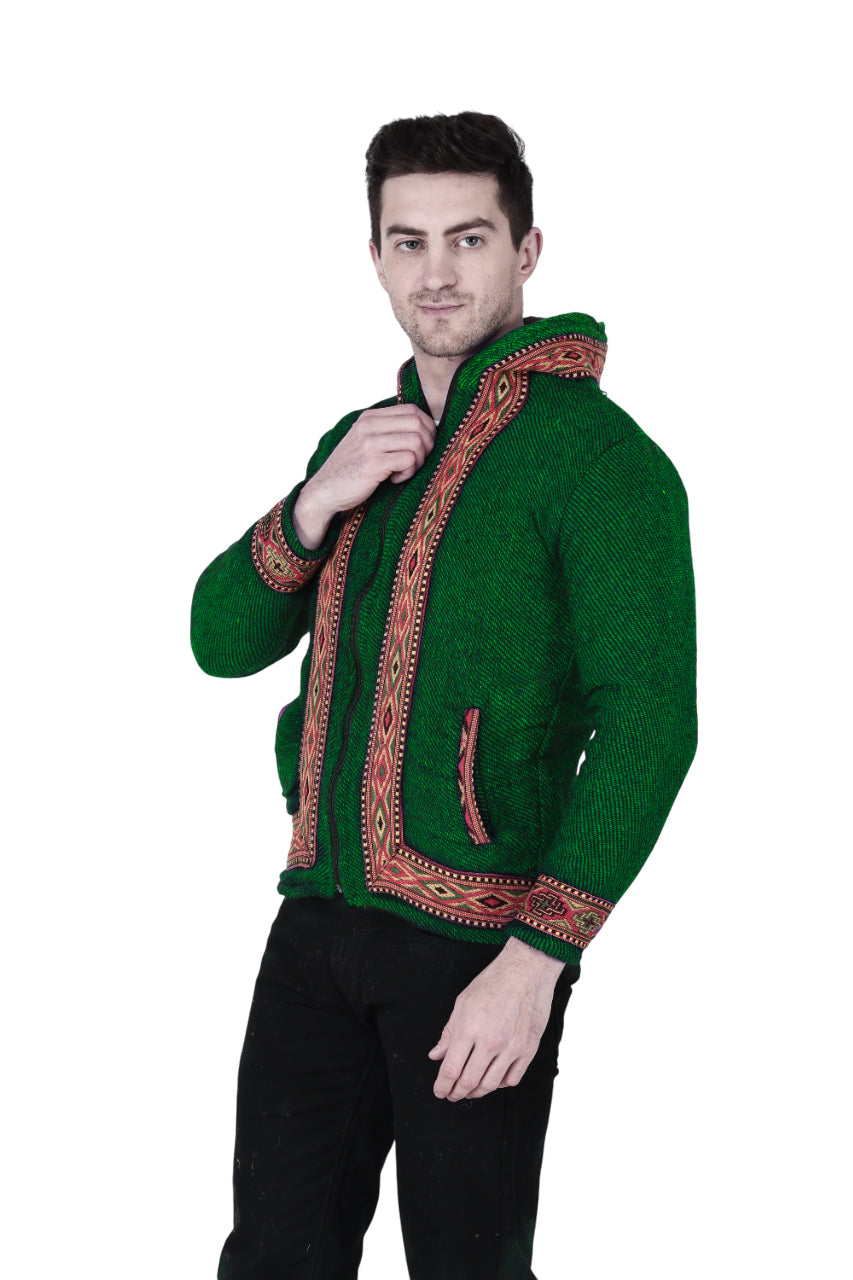 himachali hoodie for men kullu hoodie himachali hoodie kullu hoodie for men kullu hoodie for men A man wears the aruna kullu handloom Woolen Winter Wear ZIPPER HOODIE, green with border, featuring red and orange handwoven embroidery. He stands against a white background, holding the zipper near his collar and wearing black pants.