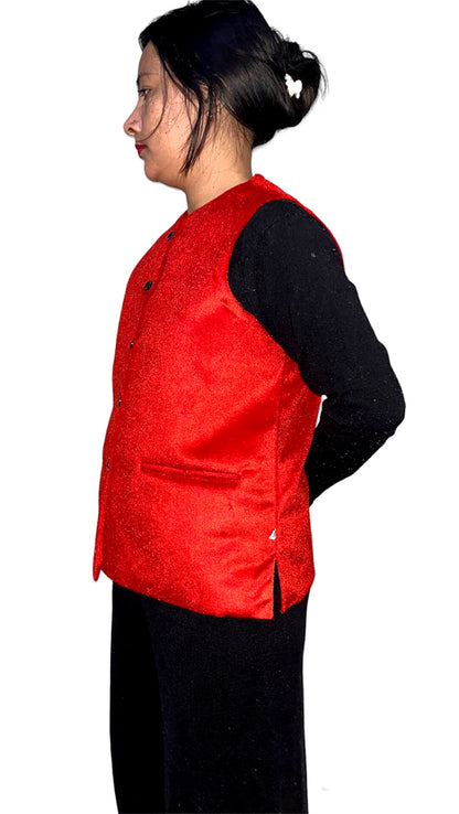 A woman with dark hair in a bun wears an aruna kullu handloom red Nehru jacket for women over a black long-sleeve shirt and black pants, standing sideways against a white background.
