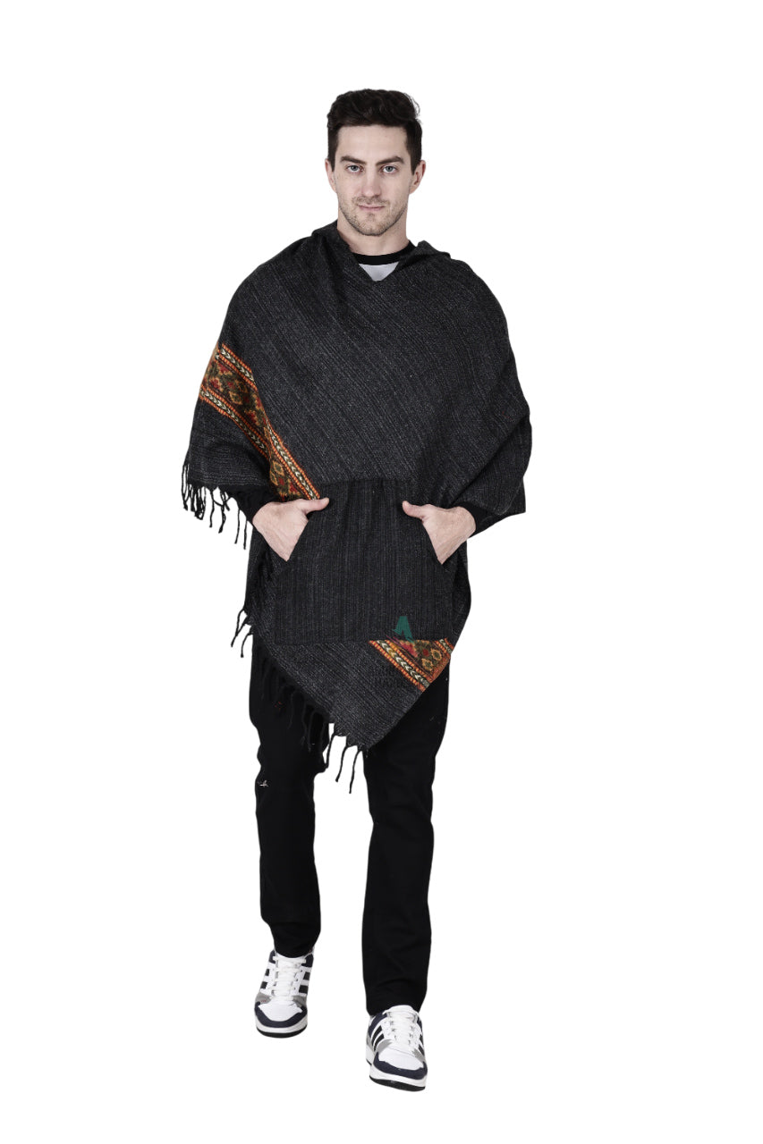 A man wearing the aruna kullu handloom kullu shawl woolen poncho with hood in black, paired with black pants and white sneakers, stands facing forward against a white background.