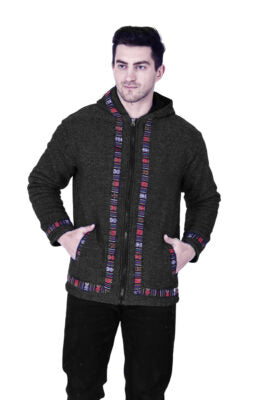 A man stands against a white background wearing the aruna kullu handloom Woolen Winter Wear ZIPPER HOODIE Jacket for MEN in grey, featuring colorful patterned trim along the zipper, cuffs, and hem with his hands in the pockets.