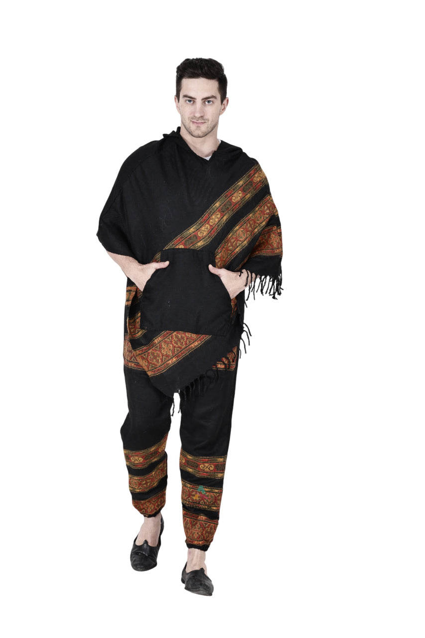 A person stands against a white background wearing the aruna kullu handloom Combo pajama and poncho black 3 patti, featuring colorful patterned bands on both pieces, fringe on the poncho edge, and their hands in the pockets.