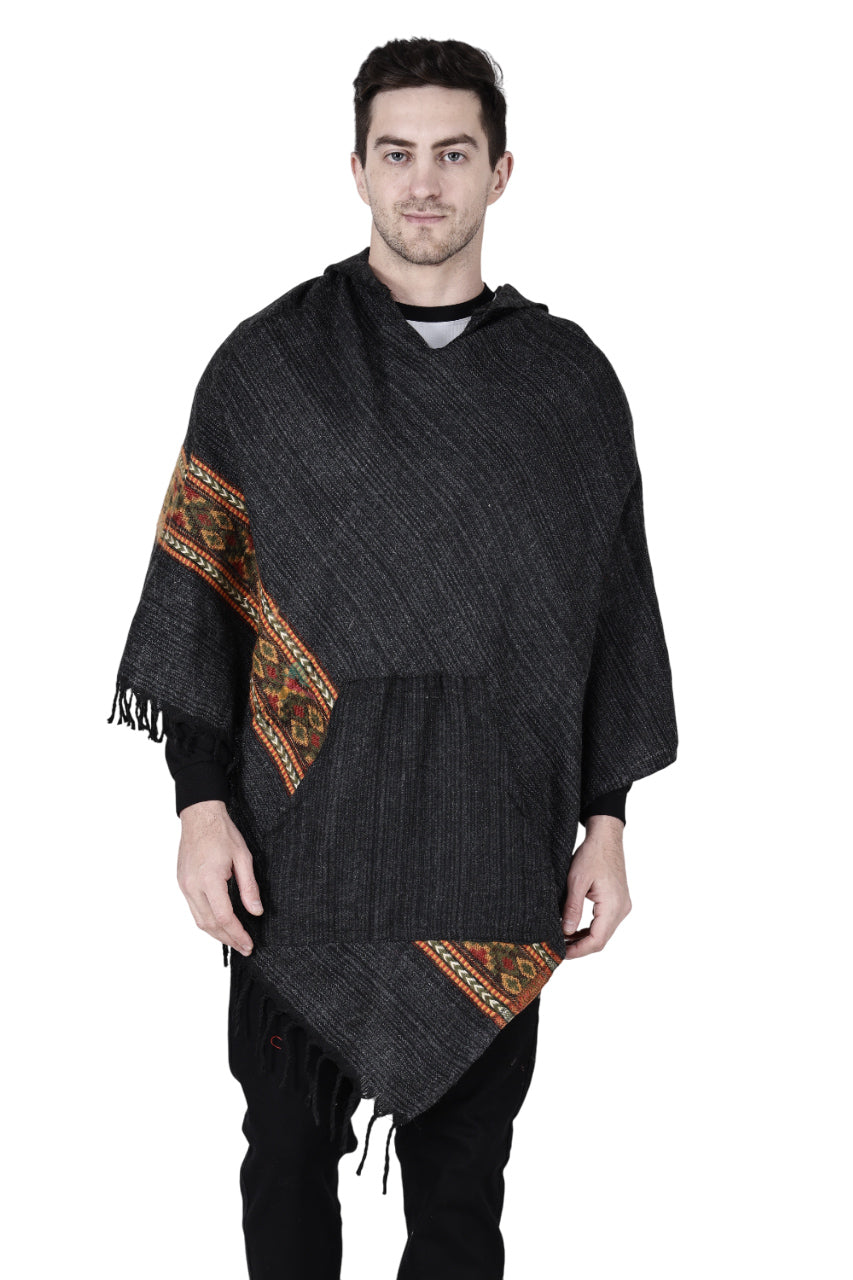 A man stands facing forward against a plain white background, wearing the aruna kullu handloom kullu shawl woolen poncho with hood in black, featuring colorful stripes and hand-woven embroidery on the sleeves and hem.