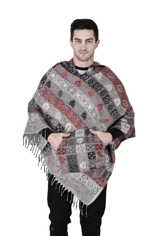A man stands facing forward with his hands in the front pocket, wearing an Aruna Kullu Handloom grey kullu shawl woolen poncho with hood, featuring red, black, and gray designs, against a plain white background.