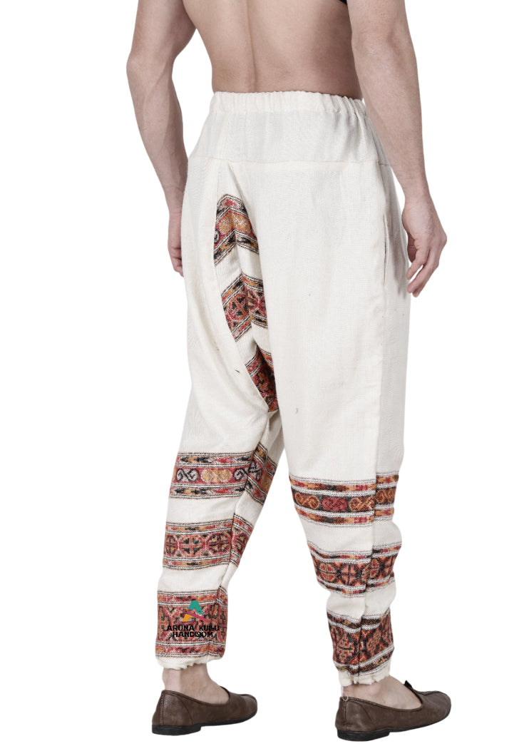 A person wearing an Aruna Kullu Handloom yoga pajama for men, loose white 3 patti, handwoven with a colorful design.