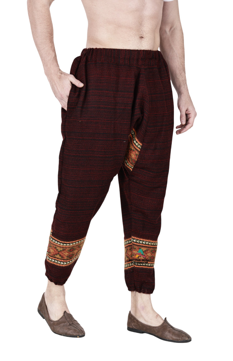 A person wears loose maroon yoga pajama for men by aruna kullu handloom, featuring decorative ankle patterns and a side pocket, paired with brown slip-on shoes; upper body not shown.
