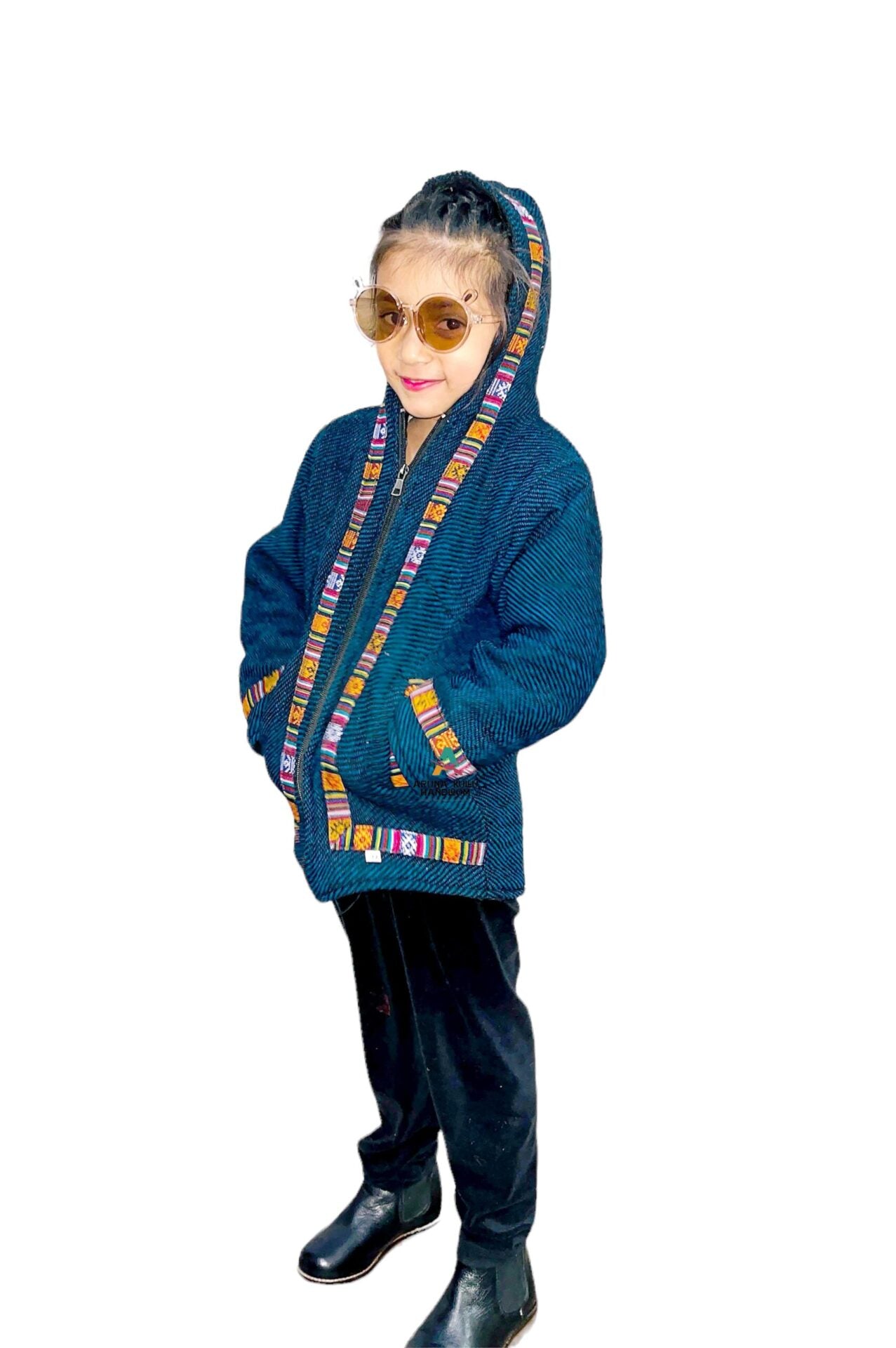 A young girl in sunglasses, black pants, and black boots wears a blue Woolen Winter Wear Zipper Hoodie for Kids with colorful trim, standing with hands in pockets against a white background.