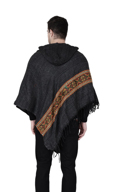 A person models the aruna kullu handloom kullu shawl woolen poncho with hood in black, featuring colorful patterned stripes and fringe, standing with their back to a white background.