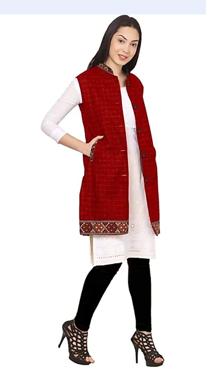 A woman wears the aruna kullu handloom check red long jacket with kullu lace work over a white kurti and black leggings, posing smiling with one foot forward against a plain white background.