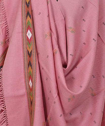 The ARUNA Women's Wool Shawl from aruna kullu handloom features pink woven fabric, subtle small embroidery, a multicolour Kinnauri geometric border, and fringed edges inspired by classic Manali shawls.