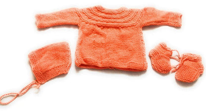 The PURE WOOL NEW BORN BABY SET ORANGE by aruna kullu handloom features a handwoven long-sleeve sweater, bonnet with ties, and booties, inspired by Himachali babywear—displayed on a white background.