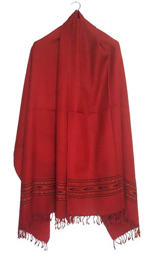 The ARUNA Premium Pure Wool Kullu Shawl Unisex by aruna kullu handloom, featuring red wool with black and red patterned borders and fringes, hangs on a hook against a white background.
