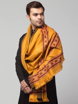 A man in a black traditional outfit drapes the aruna kullu handloom Men shawl Kullu Wool lohi, Genuine Hand Woven for Men with 3 Patti mustard design, over his shoulders against a plain light gray background.