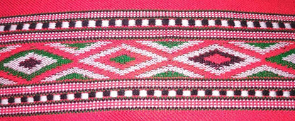 A close-up of aruna kullu handloom KULLU Patti (LACE) Border for Suits, Kurtis, and Dress Material (3 M), showcasing colorful woolen geometric patterns with diamond shapes and striped borders on a vibrant pink background.