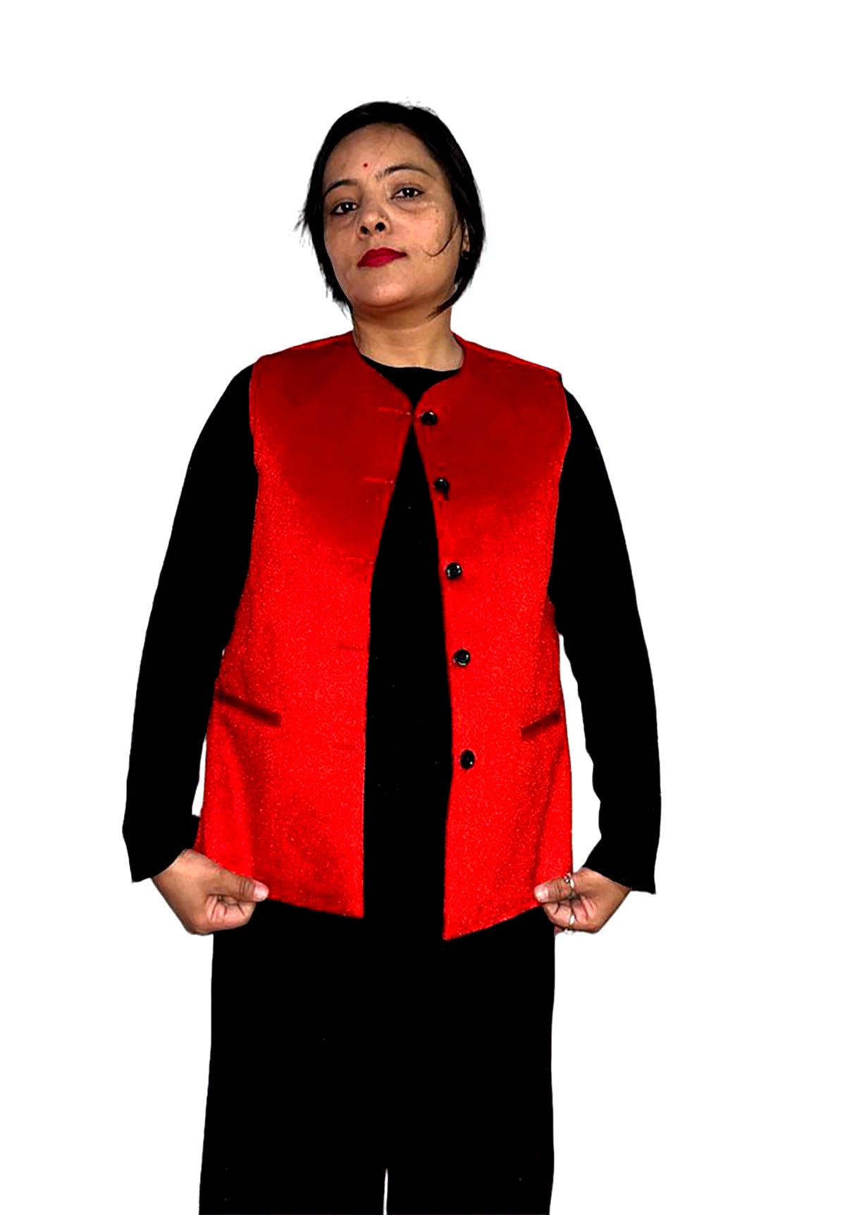 A woman poses confidently against a white background, wearing an aruna kullu handloom Nehru jacket for women in red over a black long-sleeve top and pants, holding the edges of her stylish vest.