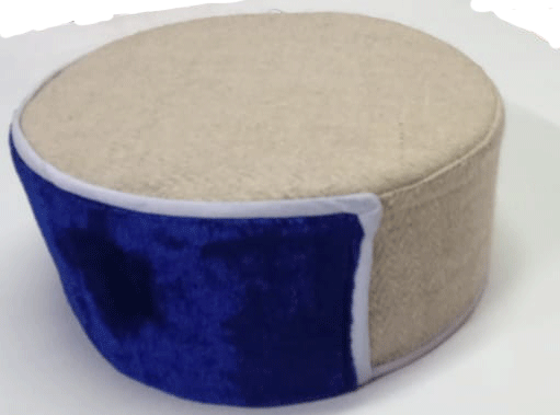 A round beige ottoman with a plush blue accent inspired by the vibrant patterns of the kullu topi VELVET BLUE KULLU TOPI from aruna kullu handloom, placed on a white surface.
