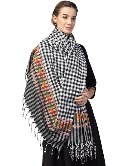 A woman wears the aruna kullu handloom kinnauri shawls ANGORA Shawl in check black, featuring beautiful Kullu weaving, colorful embroidery, and fringed edges, designed for women and girls.