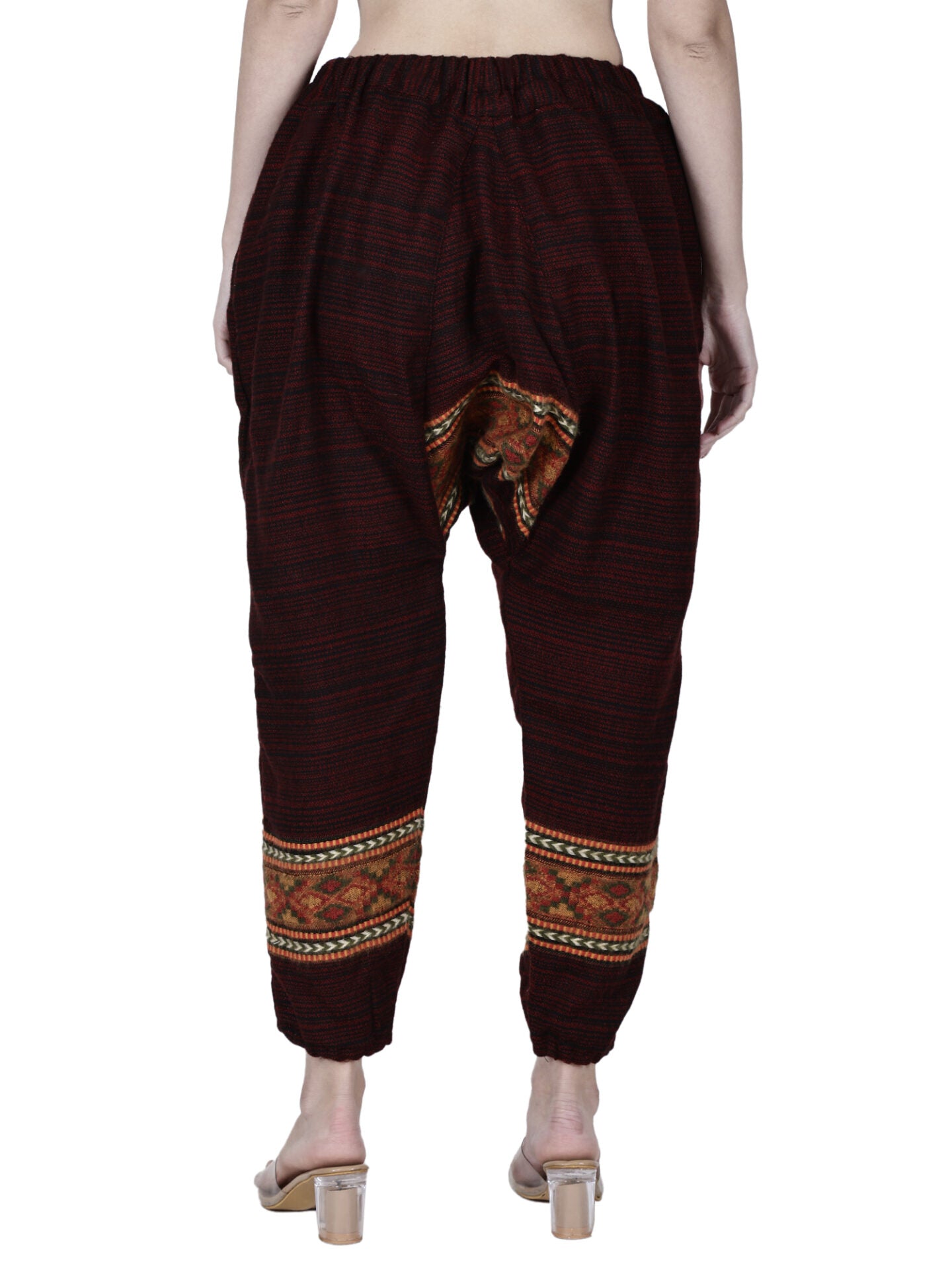 A barefoot person is shown from the back wearing aruna kullu handloom's loose yoga pajama maroon singal patti, featuring an elastic waistband and patterned detailing near the ankles and inner thighs.