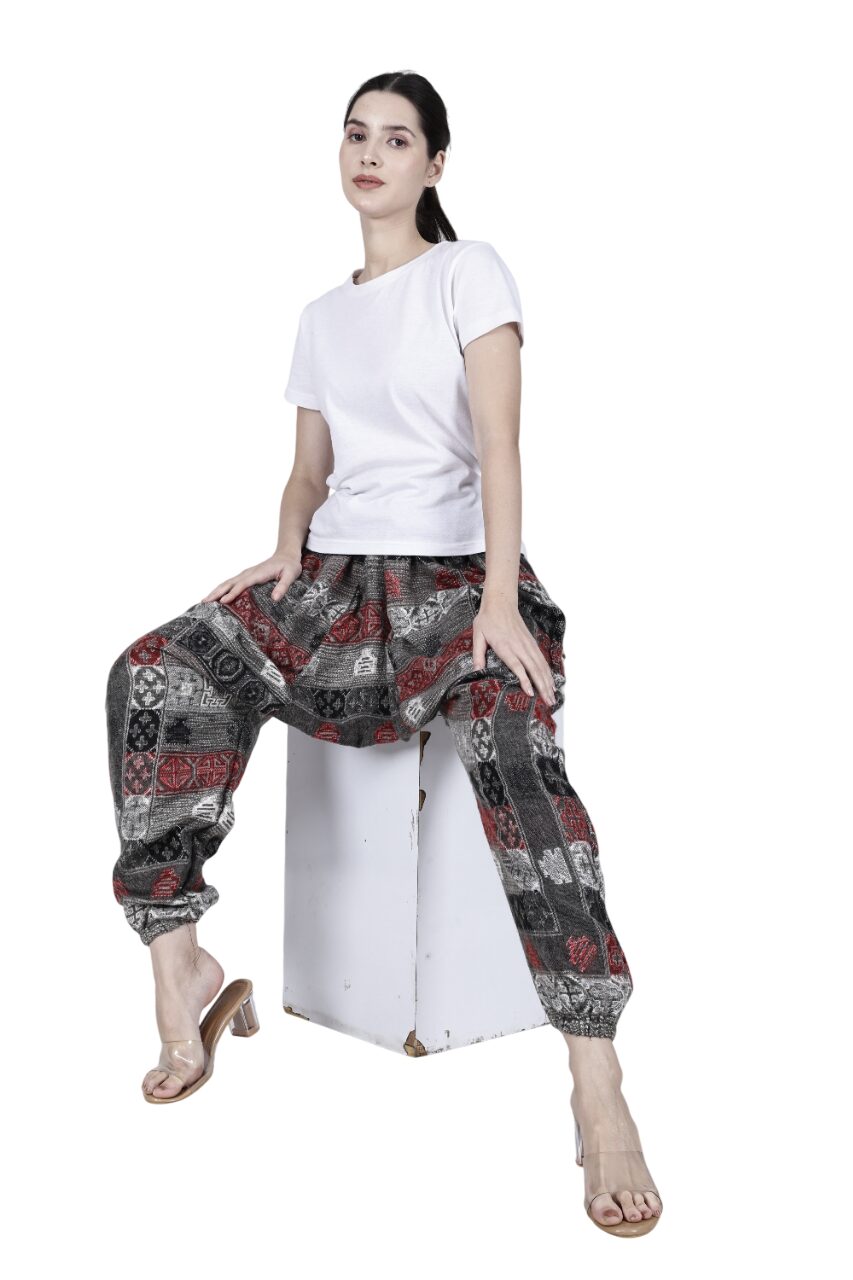 A woman sits on a white cube wearing aruna kullu handloom's Wool Super Soft Warm Pyjamas with Kullu Patti work—loose yoga pajamas for men & women. Her hair is tied back, and she wears clear heeled sandals against a white background.