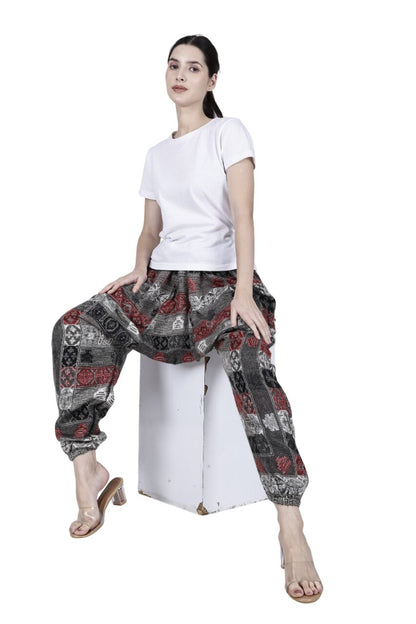 A woman sits on a white cube wearing aruna kullu handloom's Wool Super Soft Warm Pyjamas with Kullu Patti work—loose yoga pajamas for men & women. Her hair is tied back, and she wears clear heeled sandals against a white background.
