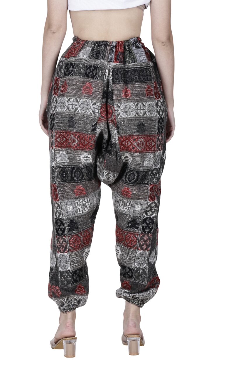 A person is shown from the back wearing Aruna Kullu Handloom's Wool Super Soft Warm Pyjamas with Kullu Patti work, featuring geometric patterns in black, red, and white and styled with clear-heeled sandals. The upper body is partially visible.