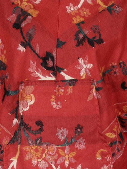 Close-up of the red Kashmiri poncho woolen poncho with hood for ladies by aruna kullu handloom, featuring a floral pattern in pink, yellow, black, and white with scattered branches and flowers across its vibrant fabric.