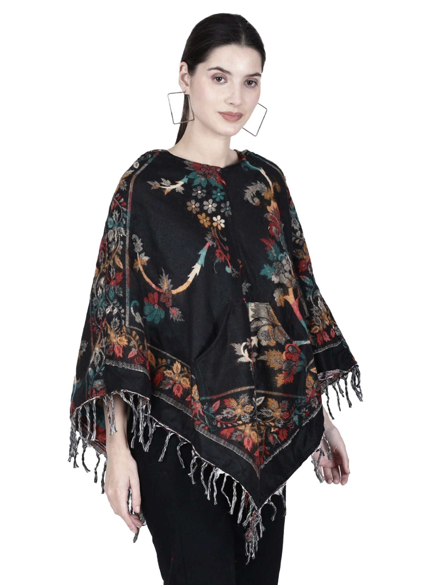 A woman wears the aruna kullu handloom Kashmiri poncho—a black, handwoven woolen poncho with hood—paired with black pants and bold earrings. Ideal for those seeking unique ladies’ poncho tops. White background.