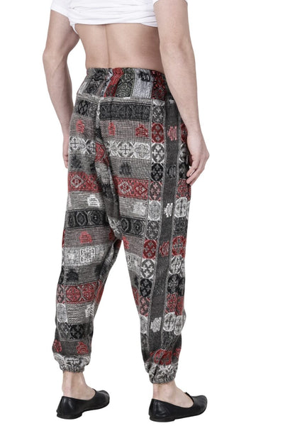A man wearing aruna kullu handloom's Pajama for men loose yoga chess design, featuring a red, black, and white pattern, stands barefoot on a plain white background, shown from the back waist down.