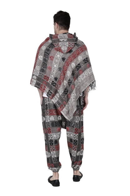 A person stands barefoot against a plain white background, wearing the aruna kullu handloom kullu shawl woolen poncho and pajama combo for men in a red, black, and white geometric pattern.