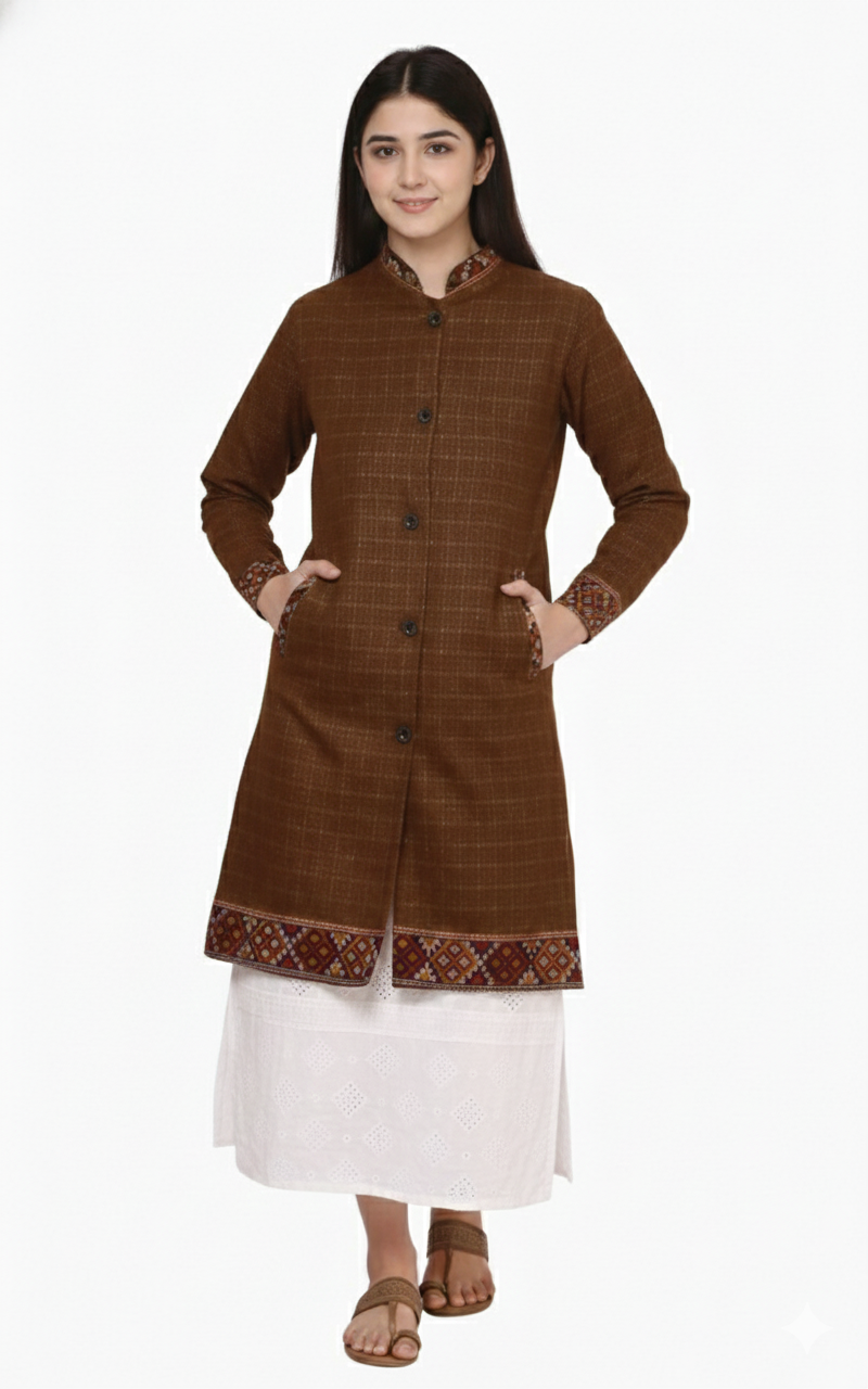 A woman models the aruna kullu handloom himachali Long Jacket for ladies with full sleeves in a brown check pattern, styled over a white skirt and brown sandals, standing against a white background.
