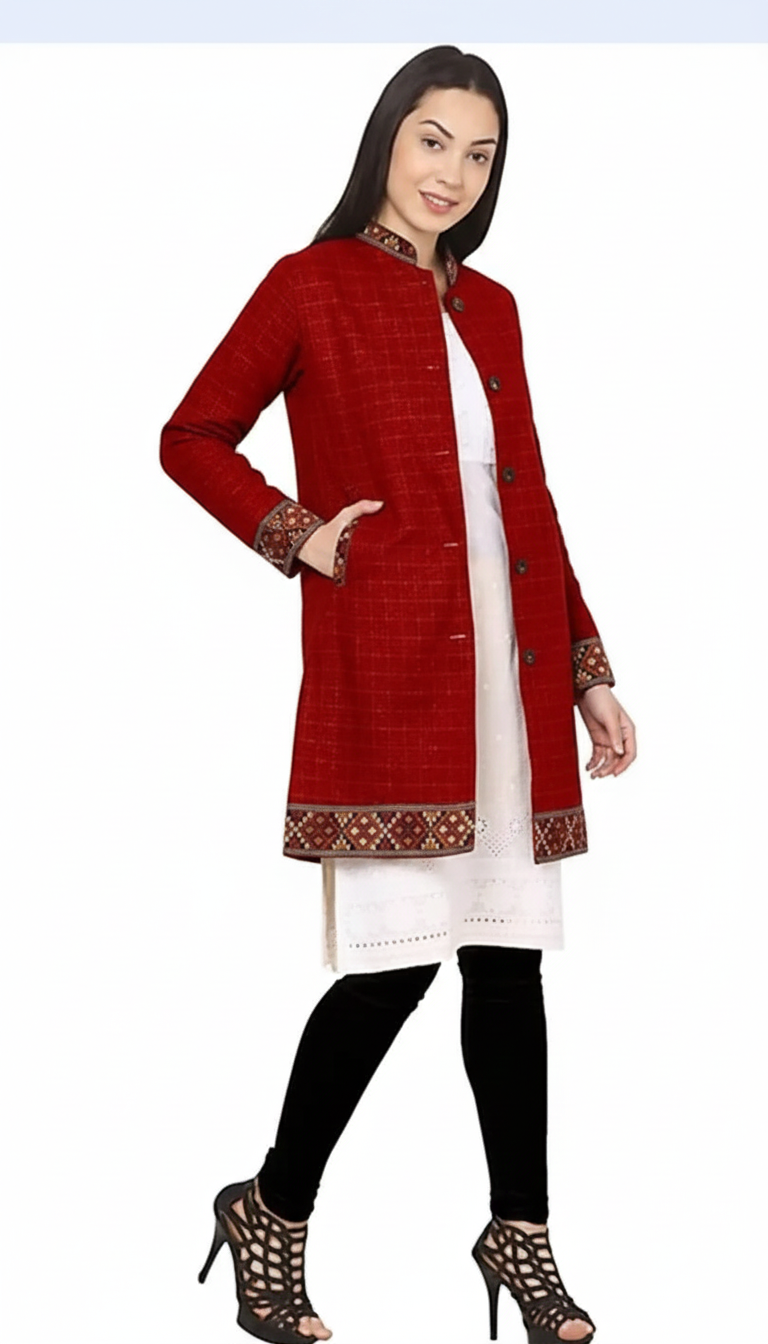 A woman wears the aruna kullu handloom himachali Long Jacket for ladies in red check with full sleeves, featuring patterned cuffs and collar, over a white kurta and black leggings, smiling with one hand in her pocket.