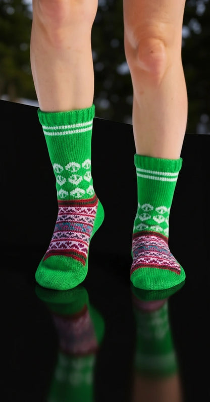A person is wearing aruna kullu handloom Woollen Traditional Hand Made Kullu Socks (Multicolour, Free Size) GREEN, featuring white patterns and colorful bands, while standing on a shiny black surface with a dark, blurred background.