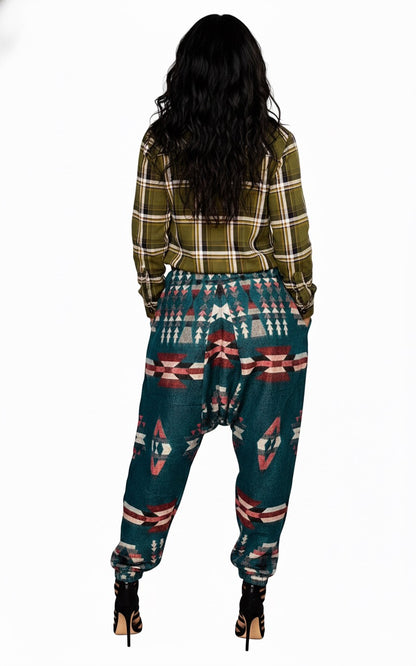 A person with long, wavy dark hair stands facing away in aruna kullu handloom’s Wool Super Soft Warm Pajamas with KULLU PATTI WORK in green. They wear black heels and stand against a white background.