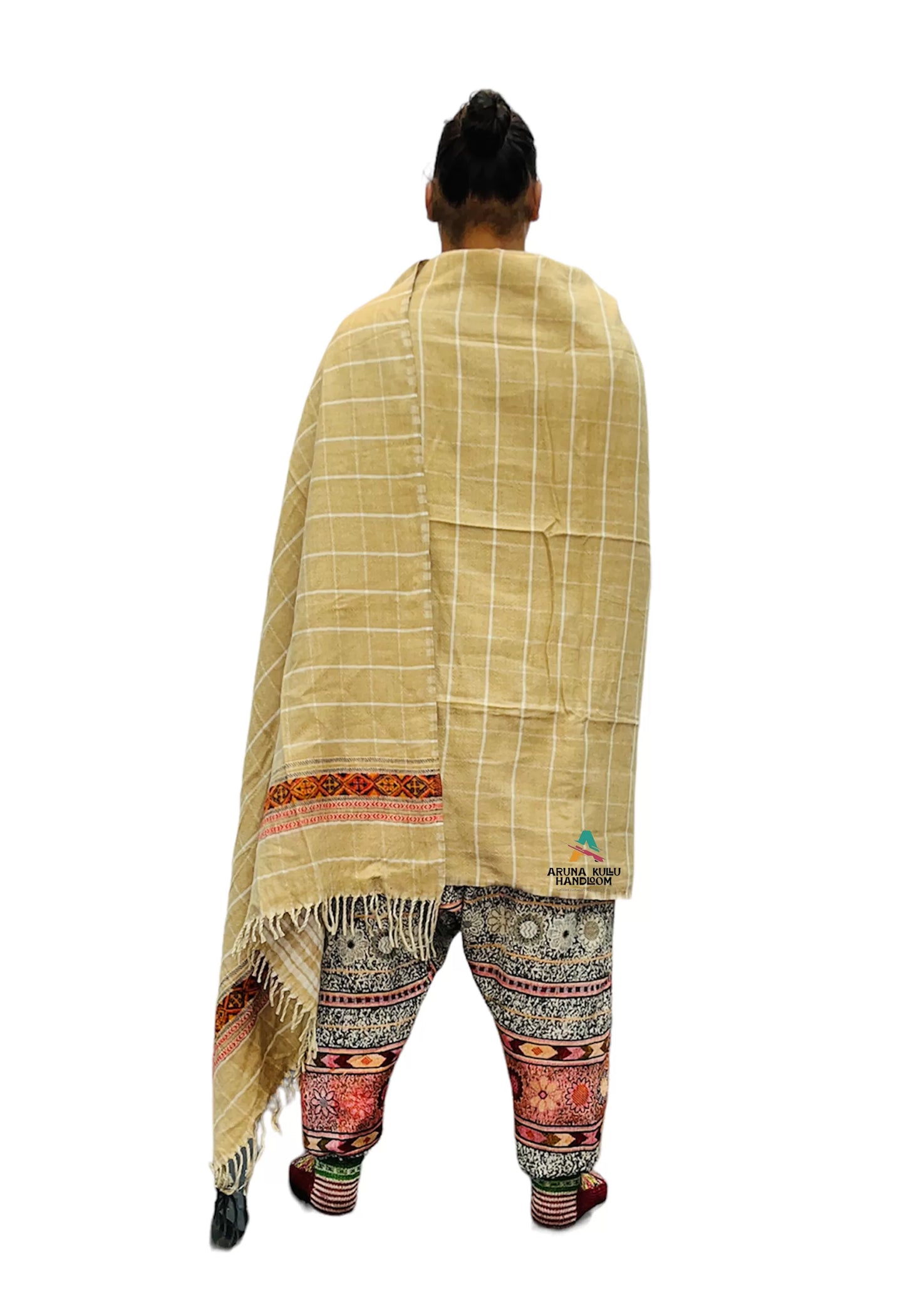 A person stands facing away, wearing the ARUNA Genuine Hand Woven Kullu Wool LOI shawl in cream with check and kullu patti work from aruna kullu handloom, draped over patterned pants, set against a plain white background.