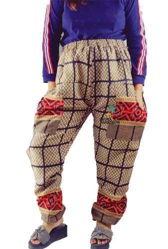 Someone is wearing aruna kullu handloom's Warm Pyjamas WITH KULLU PATTI WORK featuring a check design, paired with a blue top with red and white striped sleeves and gray slide sandals.