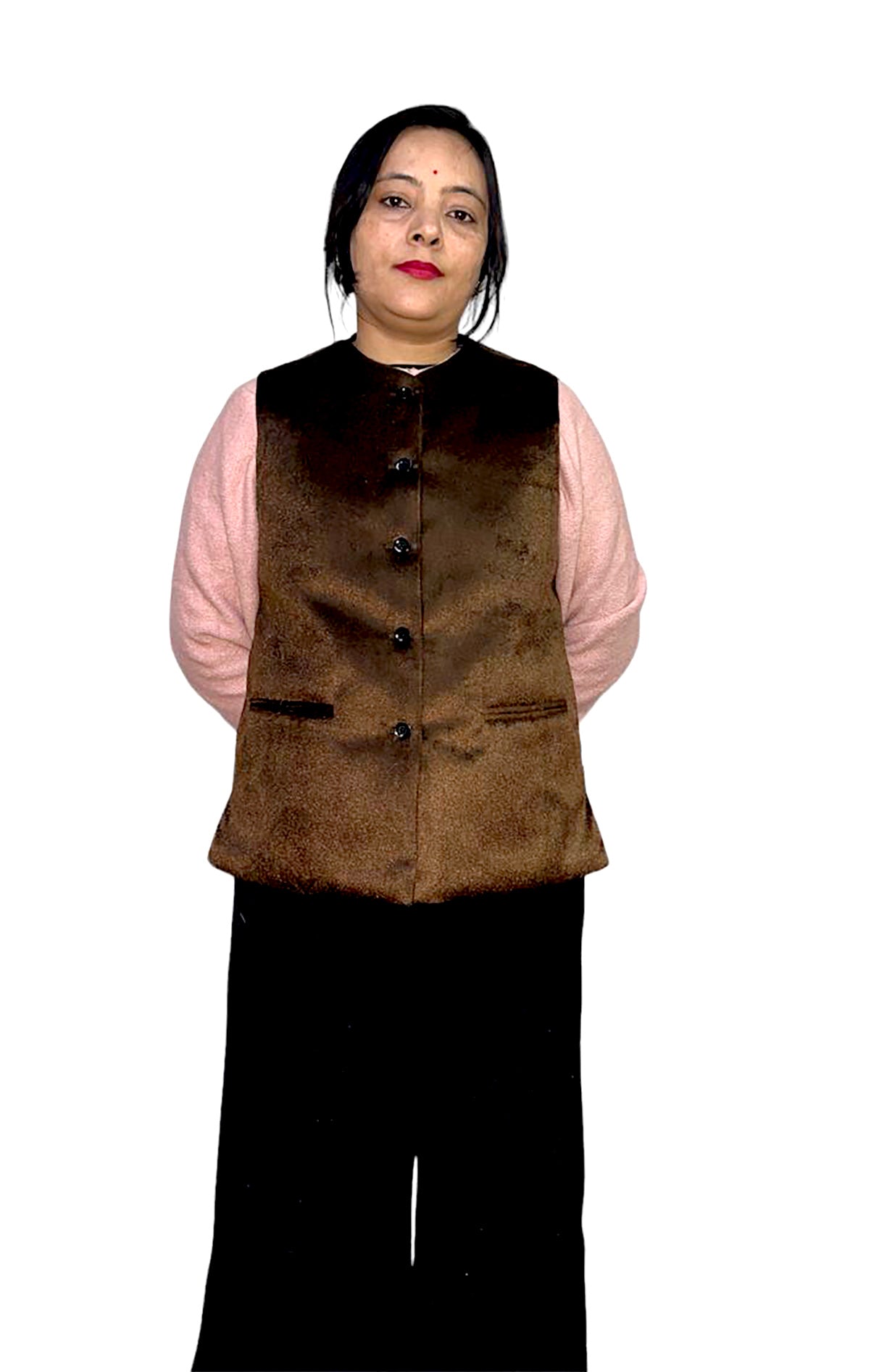 A woman with straight dark hair stands against a white background, modeling the aruna kullu handloom Rampuri Nehru jacket for light winter and party wear in brown over a pink long-sleeve top and black pants, looking at the camera with hands behind her back.