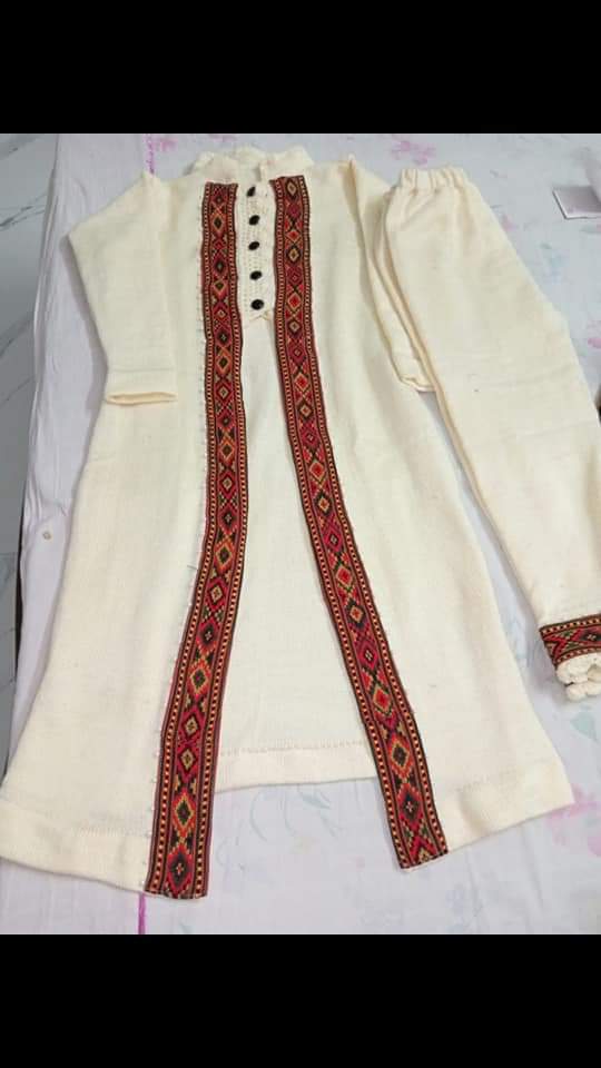 A cream kurta features long sleeves, black buttons, and two vertical embroidered KULLU Patti (LACE) borders in red, black, and orange by aruna kullu handloom. Laid flat on a light surface; pairs well with India jute shoes for a classic look.