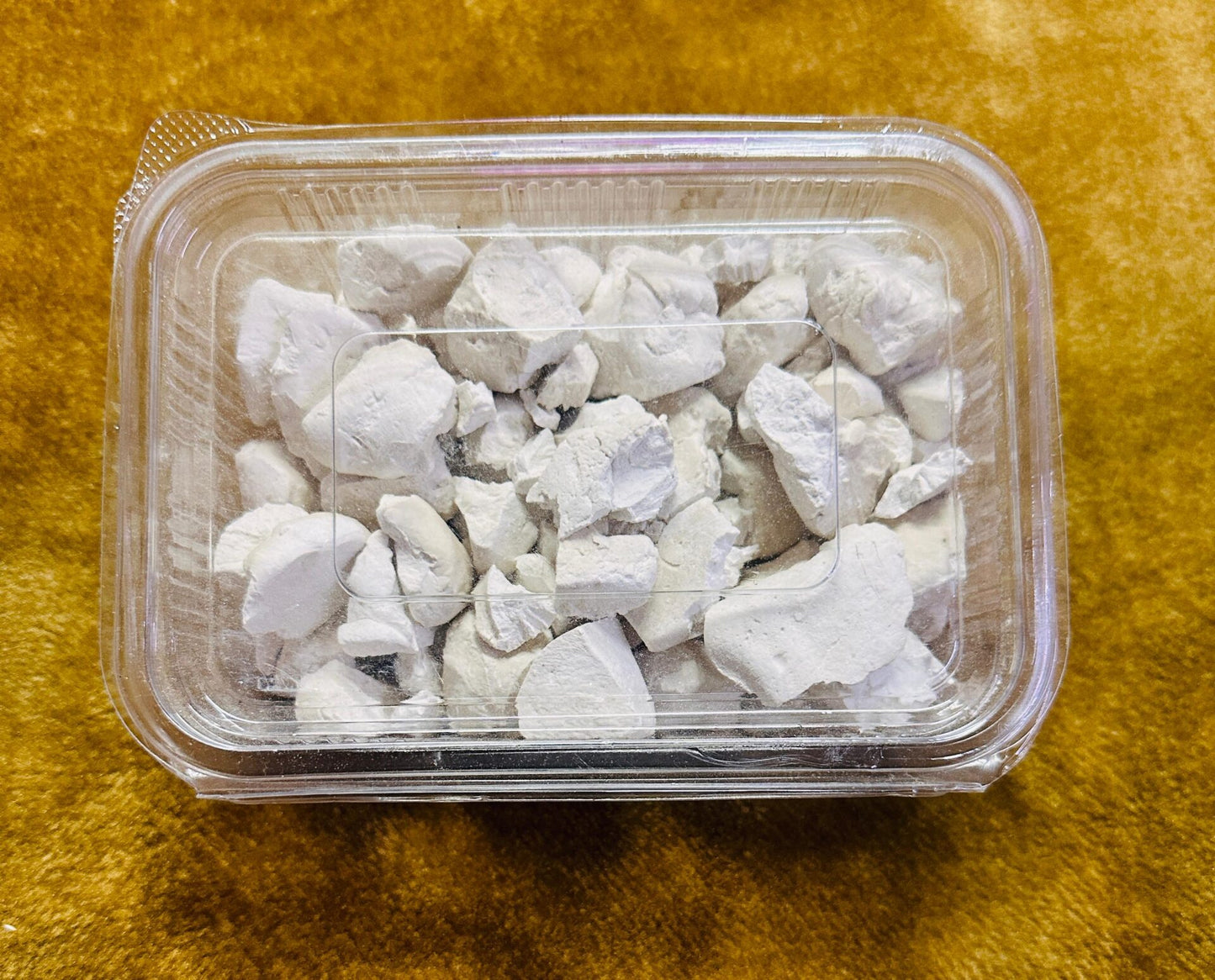 himachal products Himachal Food Products himachal herbs himachal organic products  A clear plastic container of aruna kullu handloom himachali sheera 500GM, filled with irregular white chalky chunks, sits on a yellowish-brown textured surface.