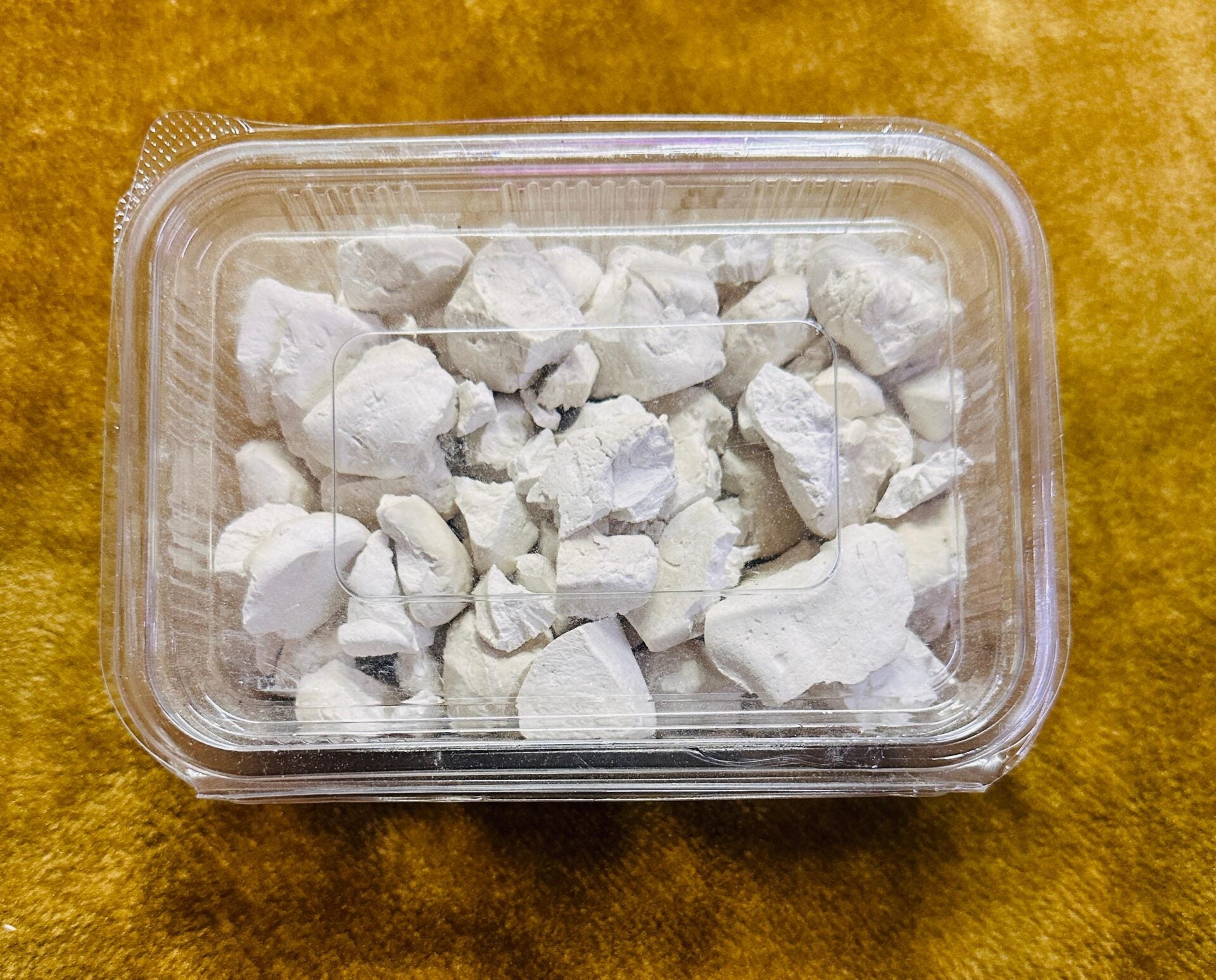 himachal products Himachal Food Products himachal herbs himachal organic products  A clear plastic container of aruna kullu handloom himachali sheera 500GM, filled with irregular white chalky chunks, sits on a yellowish-brown textured surface.