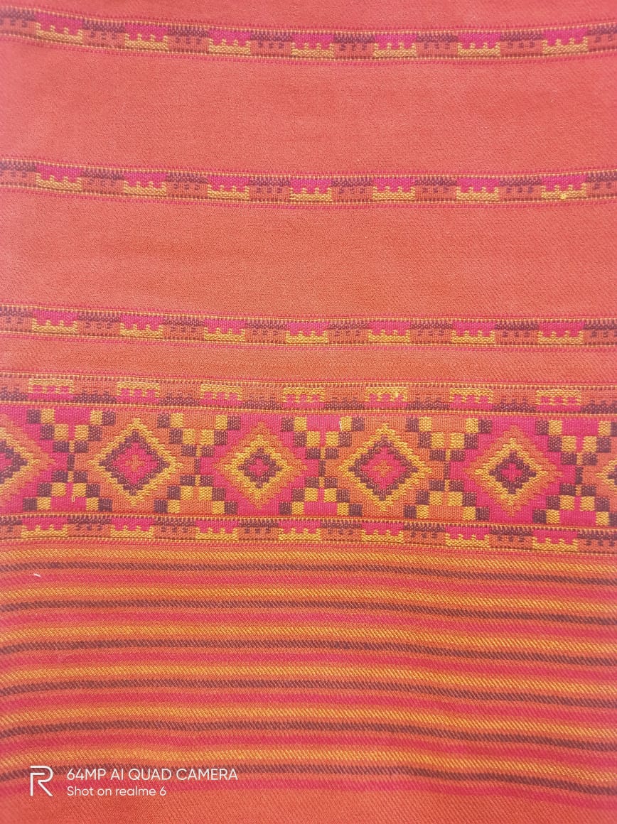 A close-up of the aruna kullu handloom Hand Woven PASHMINA RUST COLOR Shawl for women shows geometric diamond and stripe patterns in red, pink, orange, and yellow with fine embroidery. Shot on realme 6; text is visible in the lower left.