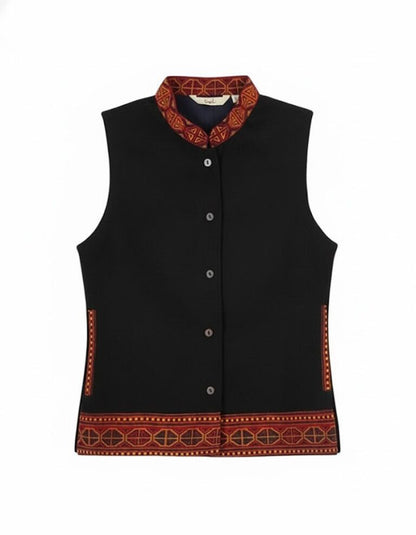 The aruna kullu handloom himachali traditional jacket is a sleeveless black woolen winter wear for women, featuring a stand collar, button-down front, and red-orange geometric embroidery—perfect for pairing with Indian ethnic outfits.